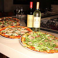 three plates of pizza and two bottles of wine